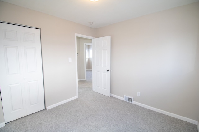 unfurnished bedroom featuring light colored carpet and a closet