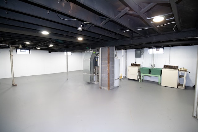 basement featuring independent washer and dryer, electric panel, sink, heating unit, and water heater