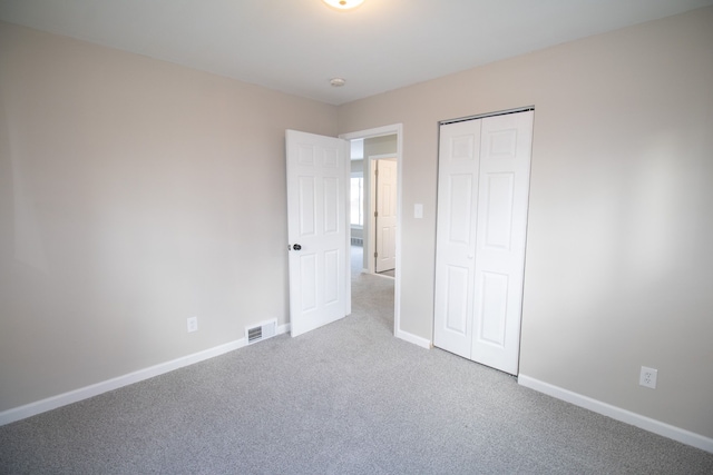 unfurnished bedroom with light carpet and a closet