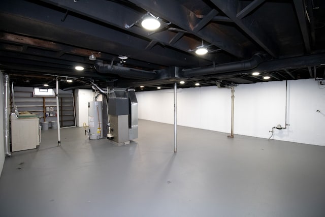 basement with water heater, heating unit, and washer / clothes dryer