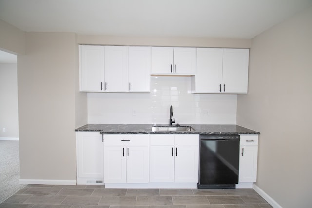 kitchen featuring dark stone countertops, light colored carpet, dishwasher, white cabinets, and sink