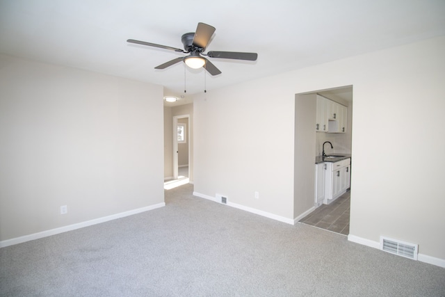 spare room featuring ceiling fan, sink, and carpet