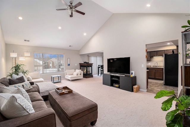 carpeted living room featuring ceiling fan, high vaulted ceiling, and sink