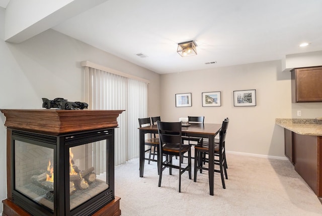 carpeted dining room featuring a multi sided fireplace