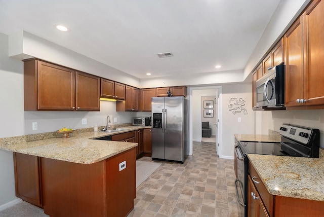 kitchen featuring light stone countertops, stainless steel appliances, kitchen peninsula, and sink