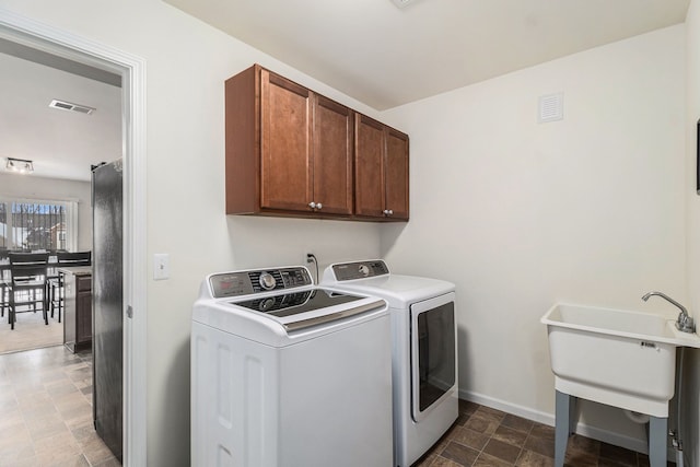 clothes washing area with sink, independent washer and dryer, and cabinets