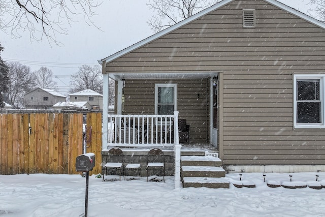 snow covered back of property with covered porch