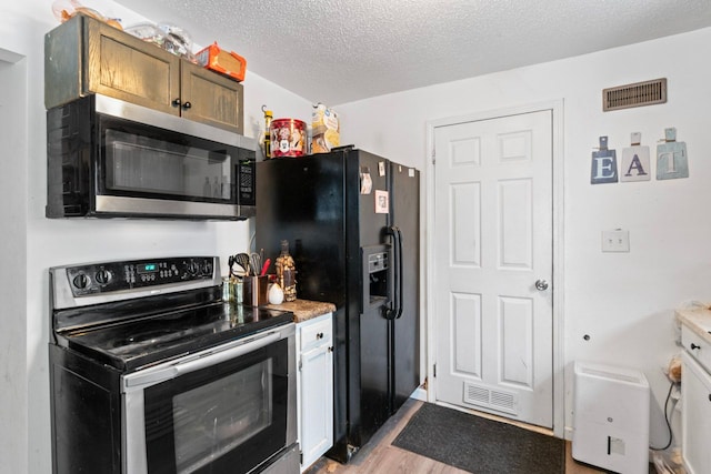 kitchen featuring a textured ceiling, appliances with stainless steel finishes, and light wood-type flooring