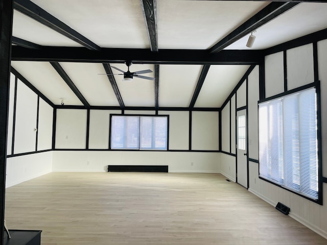 spare room featuring lofted ceiling with beams, light wood-type flooring, and a wealth of natural light