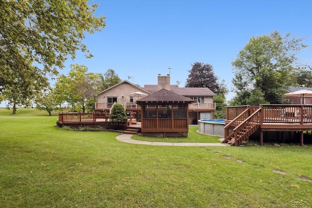 rear view of house with a gazebo, a swimming pool side deck, and a lawn