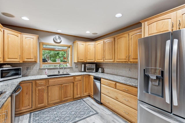 kitchen featuring light stone countertops, backsplash, appliances with stainless steel finishes, and sink