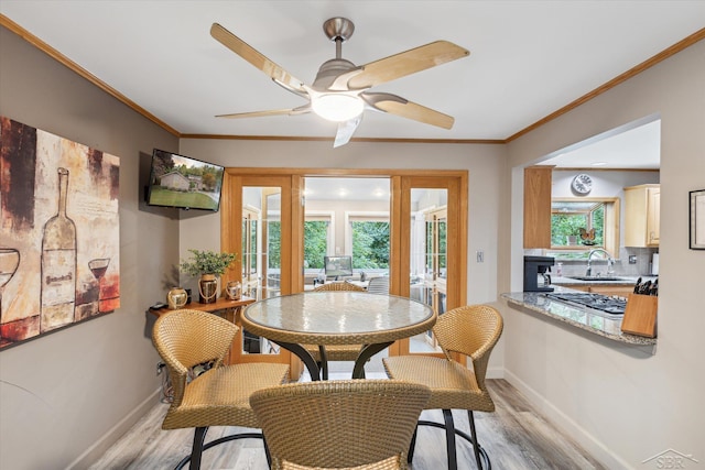 dining space with french doors, light hardwood / wood-style floors, sink, ceiling fan, and crown molding