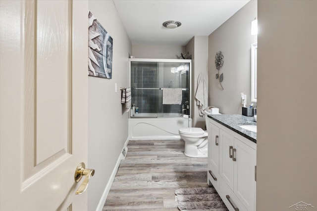 full bathroom featuring combined bath / shower with glass door, vanity, toilet, and hardwood / wood-style flooring