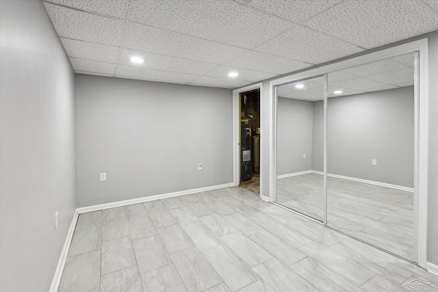 unfurnished bedroom featuring water heater, a closet, and a drop ceiling