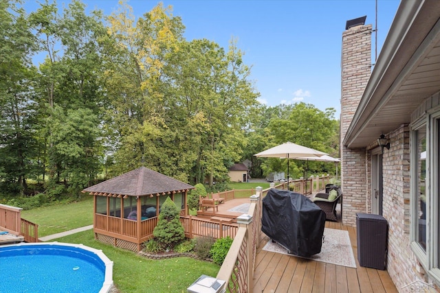 view of pool featuring a wooden deck, a sunroom, a lawn, and grilling area