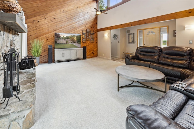 living room with ceiling fan, a fireplace, wood walls, a towering ceiling, and carpet flooring