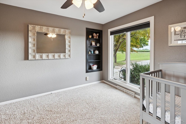 bedroom with ceiling fan, a nursery area, and carpet floors