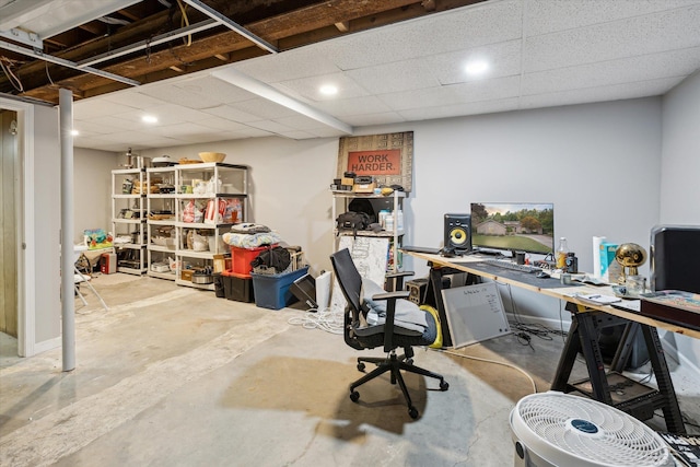 office with a drop ceiling, a workshop area, and concrete flooring