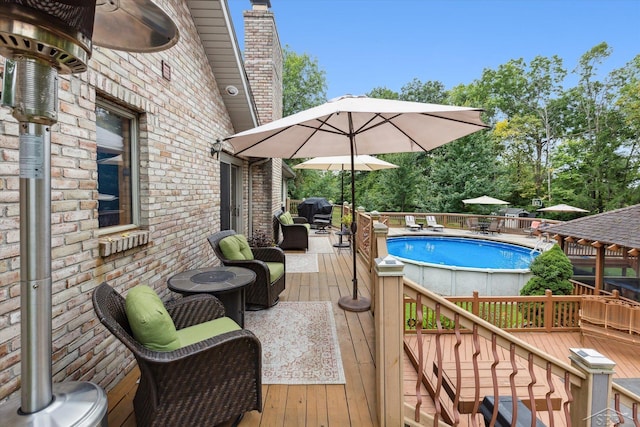 view of pool with grilling area and a deck