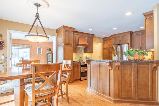 kitchen featuring premium range hood, backsplash, hanging light fixtures, and stainless steel appliances