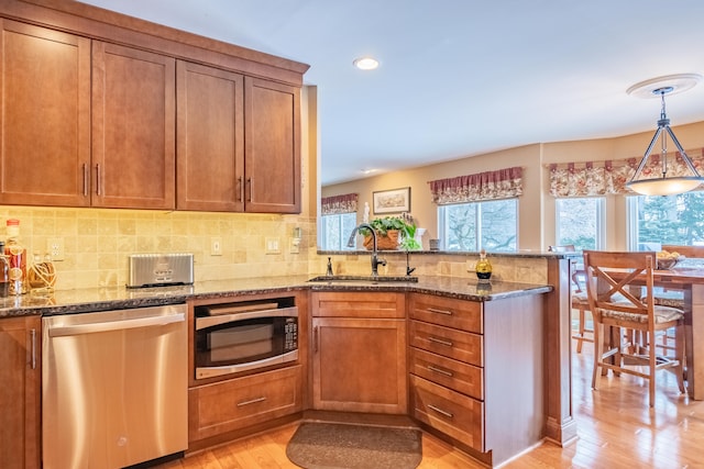 kitchen featuring sink, pendant lighting, stainless steel appliances, and dark stone counters