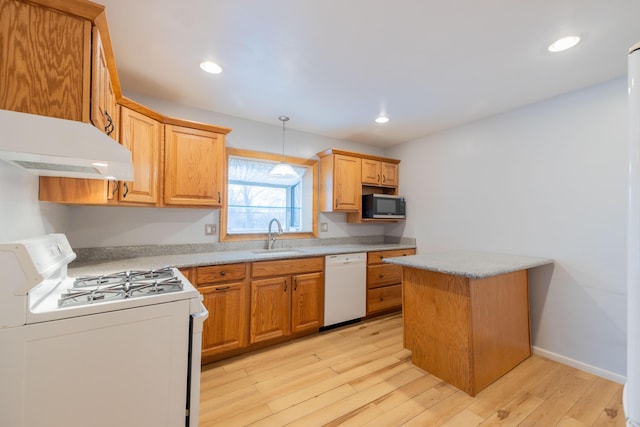 kitchen featuring pendant lighting, sink, white appliances, and light wood-type flooring