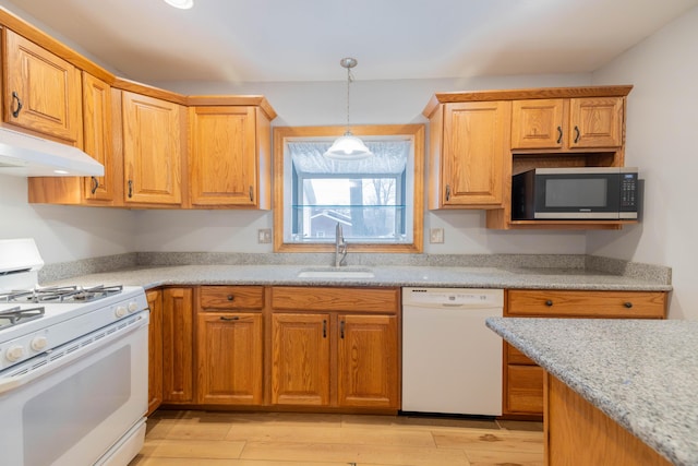 kitchen featuring light wood-type flooring, sink, pendant lighting, and white appliances