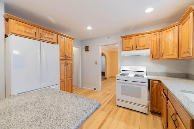 kitchen featuring light hardwood / wood-style floors, light stone counters, and white appliances