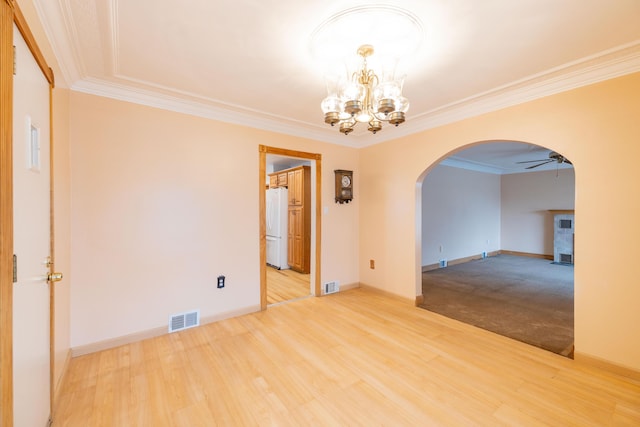 empty room featuring ceiling fan with notable chandelier, hardwood / wood-style flooring, and ornamental molding