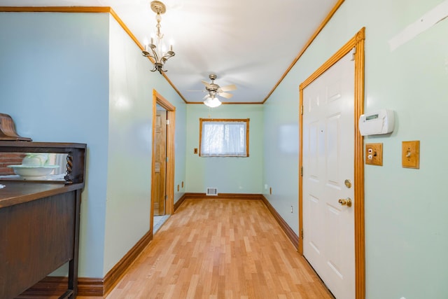 hall with an inviting chandelier, ornamental molding, and light hardwood / wood-style flooring