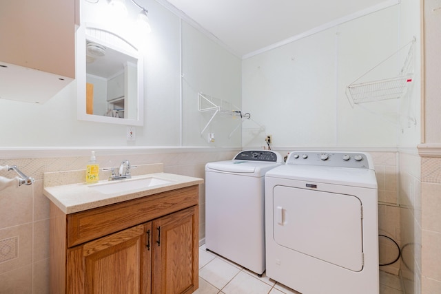 clothes washing area featuring washing machine and dryer, sink, tile walls, light tile patterned flooring, and crown molding