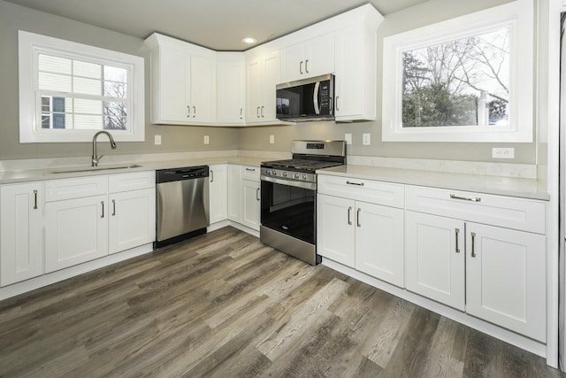 kitchen with dark wood-type flooring, appliances with stainless steel finishes, sink, and white cabinetry