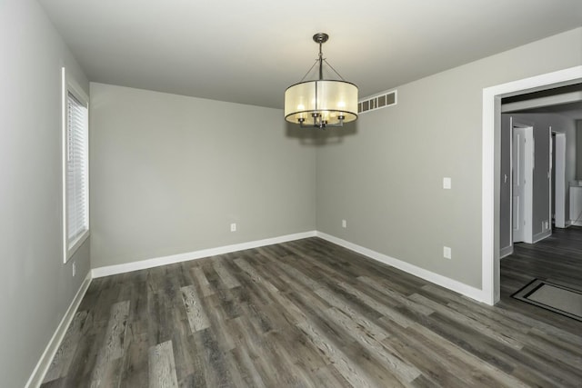 spare room with a chandelier and dark hardwood / wood-style floors