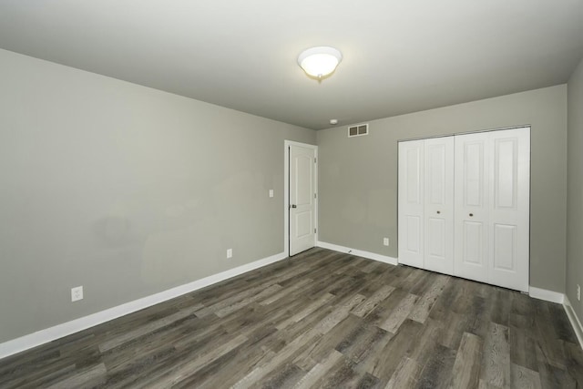 unfurnished bedroom featuring a closet and dark hardwood / wood-style flooring