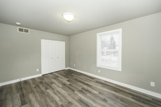 unfurnished bedroom featuring a closet and dark hardwood / wood-style floors