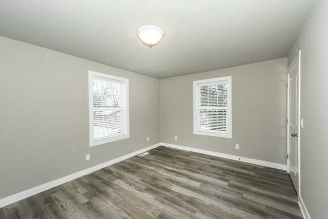 spare room with dark wood-type flooring and plenty of natural light