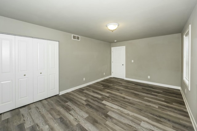 unfurnished bedroom featuring dark hardwood / wood-style floors and a closet