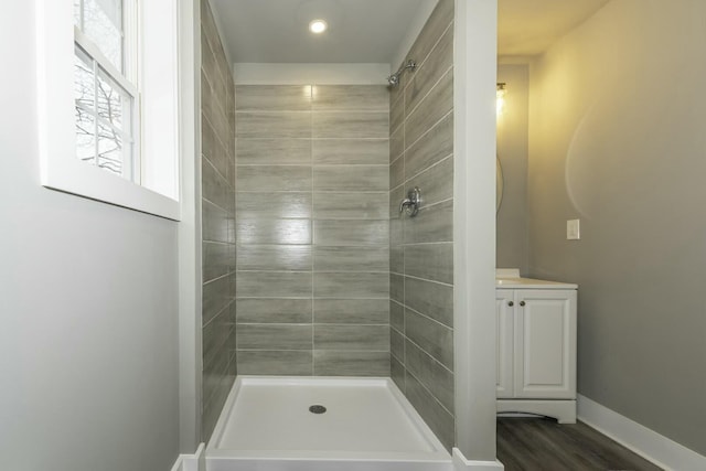 bathroom featuring wood-type flooring, vanity, and a tile shower