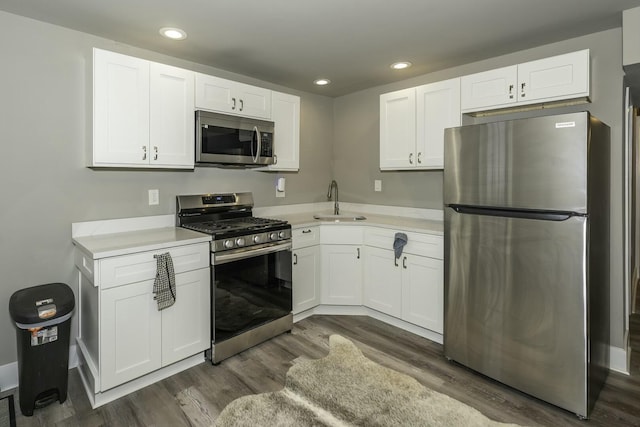 kitchen with dark wood-type flooring, stainless steel appliances, white cabinets, and sink