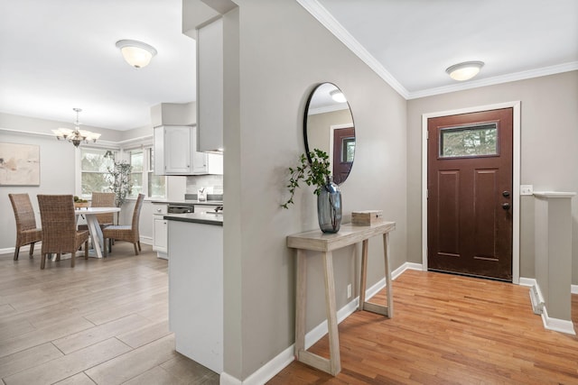 foyer entrance featuring light wood-type flooring, ornamental molding, and a notable chandelier