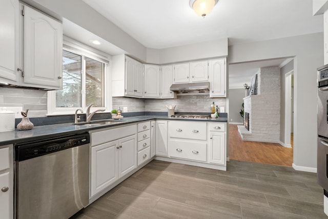 kitchen featuring appliances with stainless steel finishes, a fireplace, white cabinets, and sink