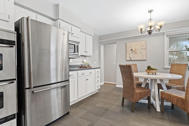 kitchen featuring stainless steel appliances, white cabinetry, and decorative light fixtures