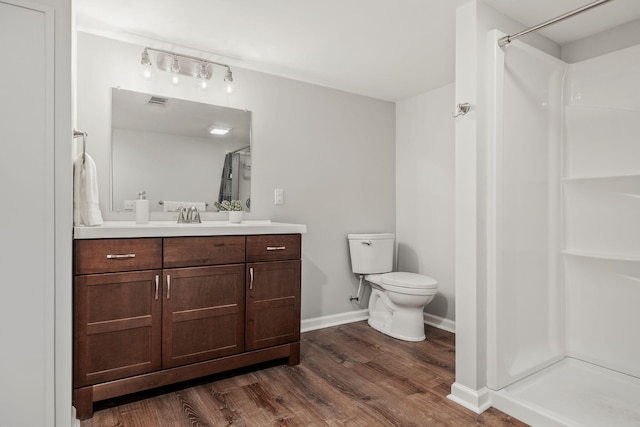 bathroom with hardwood / wood-style flooring, a shower, toilet, and vanity