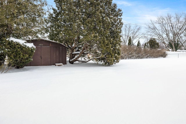 snowy yard with a storage shed