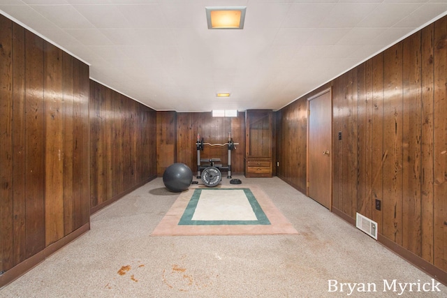 exercise area featuring light carpet and wooden walls