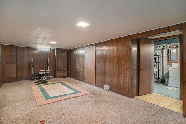 interior space with light colored carpet, wooden walls, washer / dryer, and electric panel