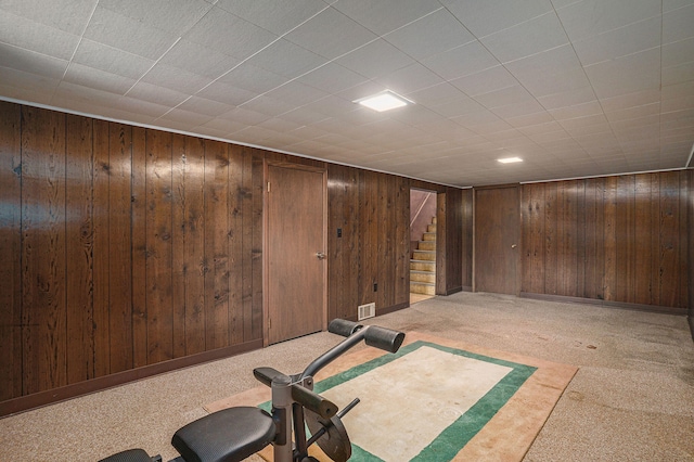 workout room with carpet floors and wood walls