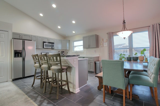 kitchen with stainless steel appliances, a kitchen island, gray cabinets, and decorative light fixtures