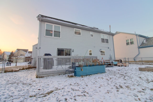 snow covered back of property with a wooden deck