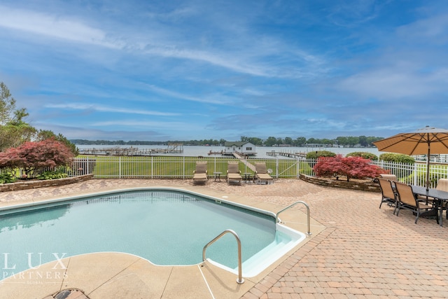 view of pool featuring a water view and a patio